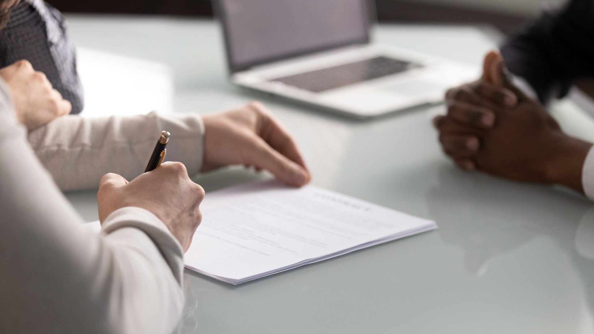 Personne prenant des notes sur un bureau tout en utilisant un ordinateur, gestion administrative en cours.