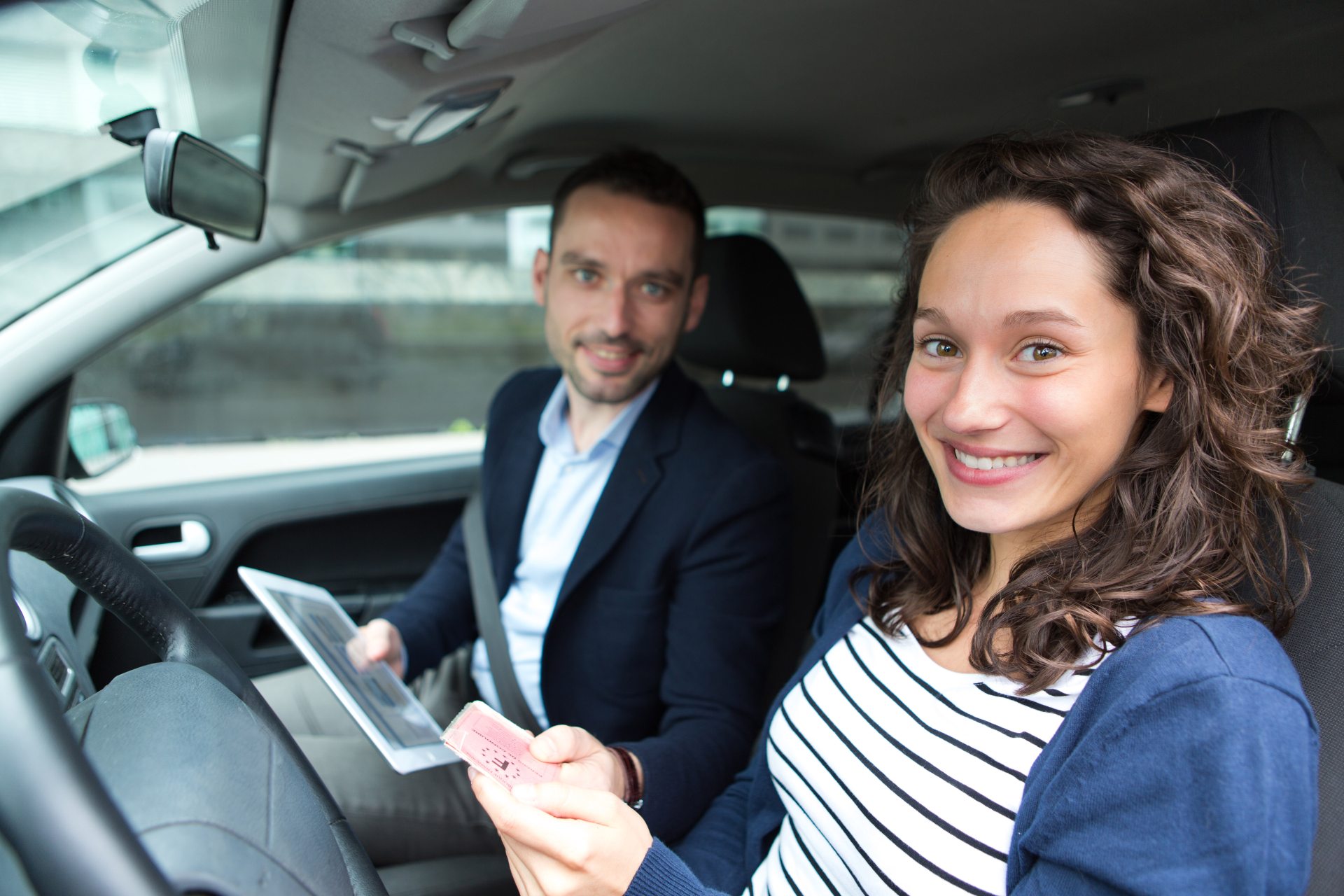 Homme et femme souriant ensemble à l'intérieur d'une voiture, symbolisant le bonheur et la satisfaction des clients après un service automobile.