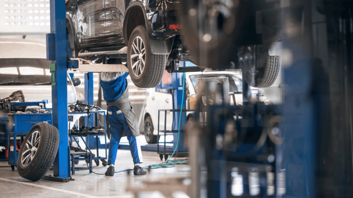 Mécanicien réparant une voiture surélevée dans un garage, entretien et réparation de véhicules