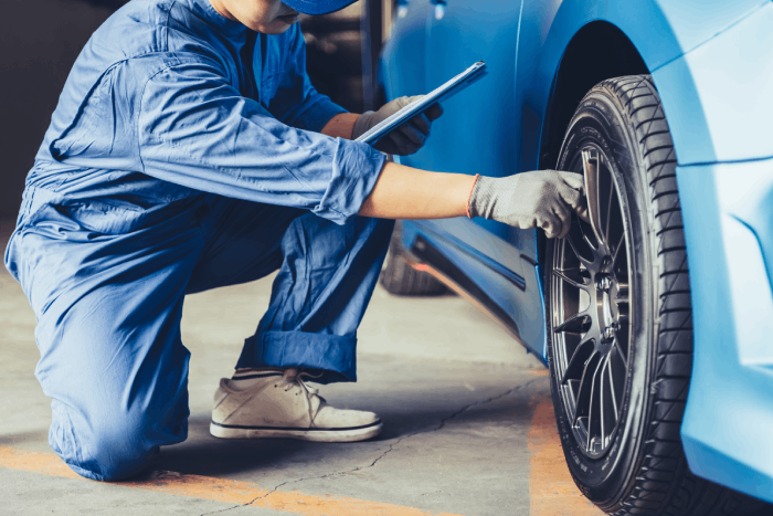 Homme vérifiant l'état d'un pneu, contrôle de sécurité et entretien automobile.